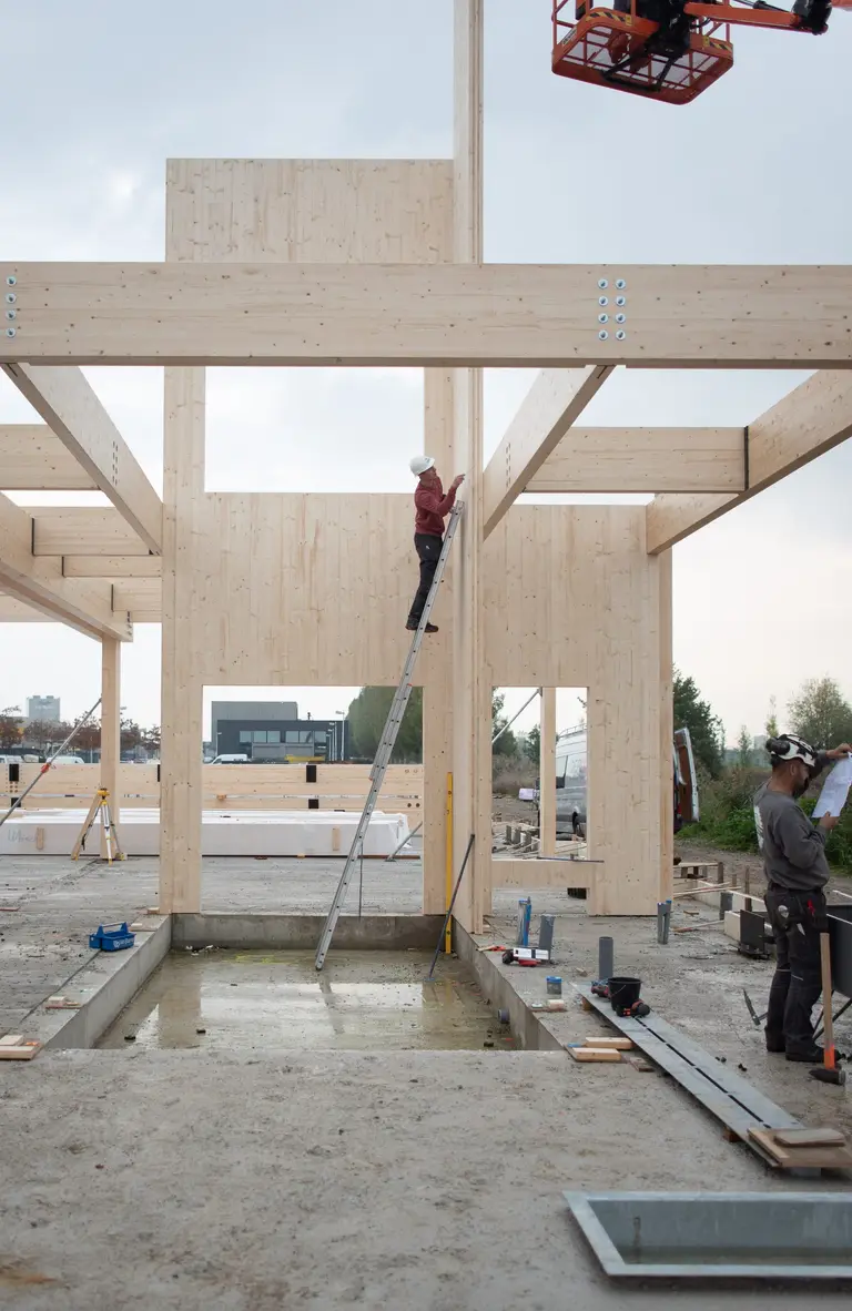 Massief houten draagconstructie in aanbouw met hijskraan