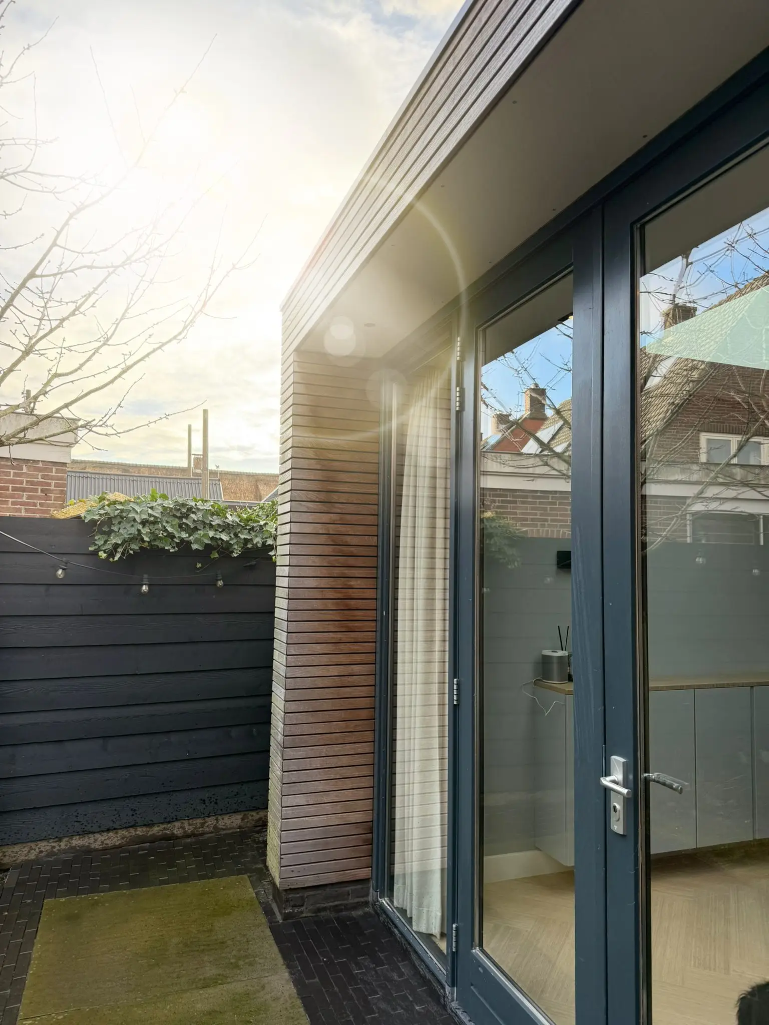 Aanbouw met grote glaspartij, verlicht in de schemering