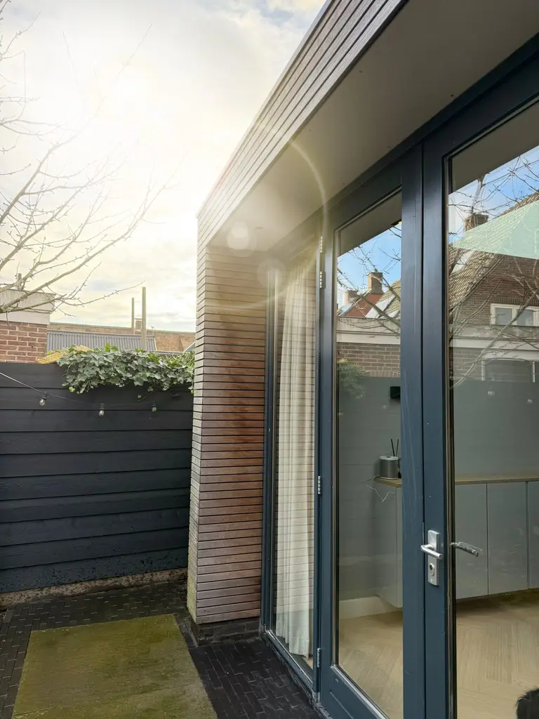 Aanbouw met grote glaspartij, verlicht in de schemering