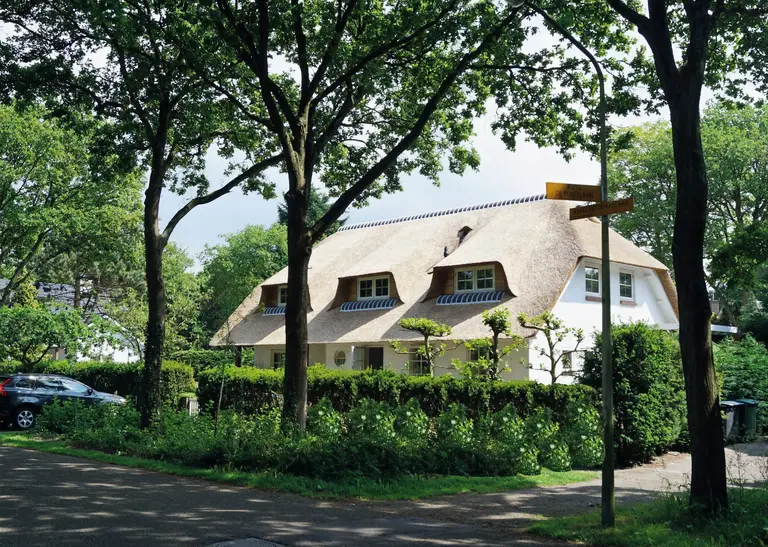 Vrijstaande woning met rieten kap tussen de bomen, gerealiseerd door Kampinga Bouw