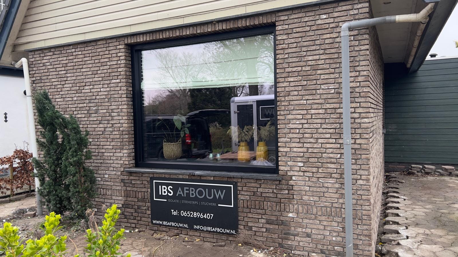 Gevel met grijsbruine steenstrips en IBS Afbouw-bord na renovatie, woonhuis Andijk (ná-foto)