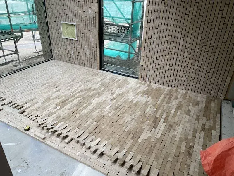 Leggen van de gebakken vloerstrips in het atrium, gemeentehuis Katwijk