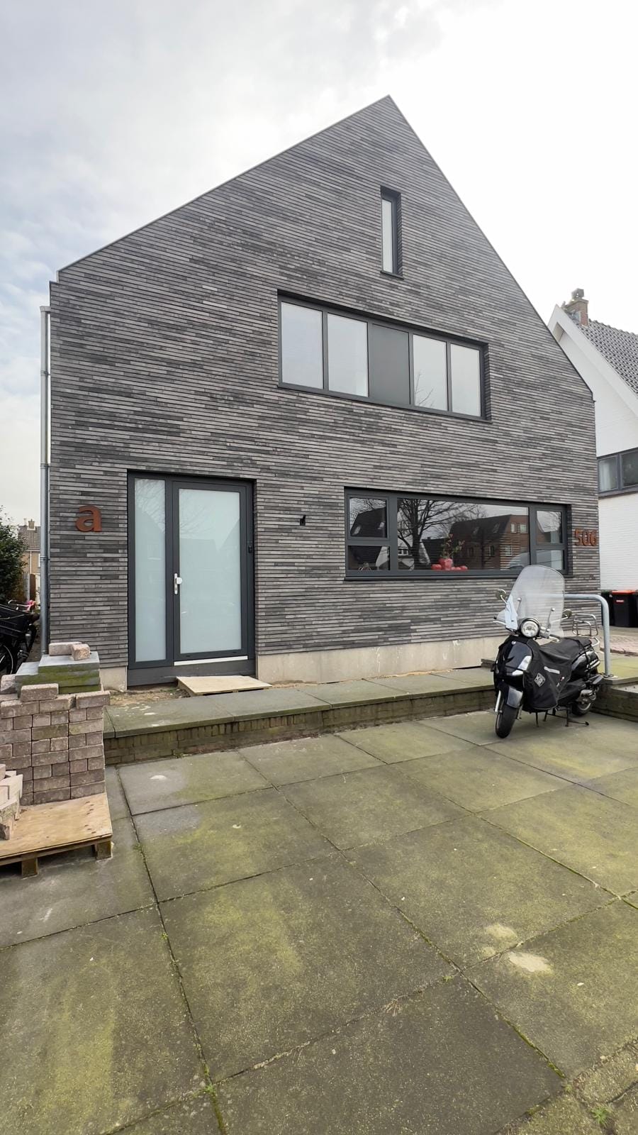 Vooraanzicht van de nieuwbouwwoning met grijze steenstrips, Heiloo