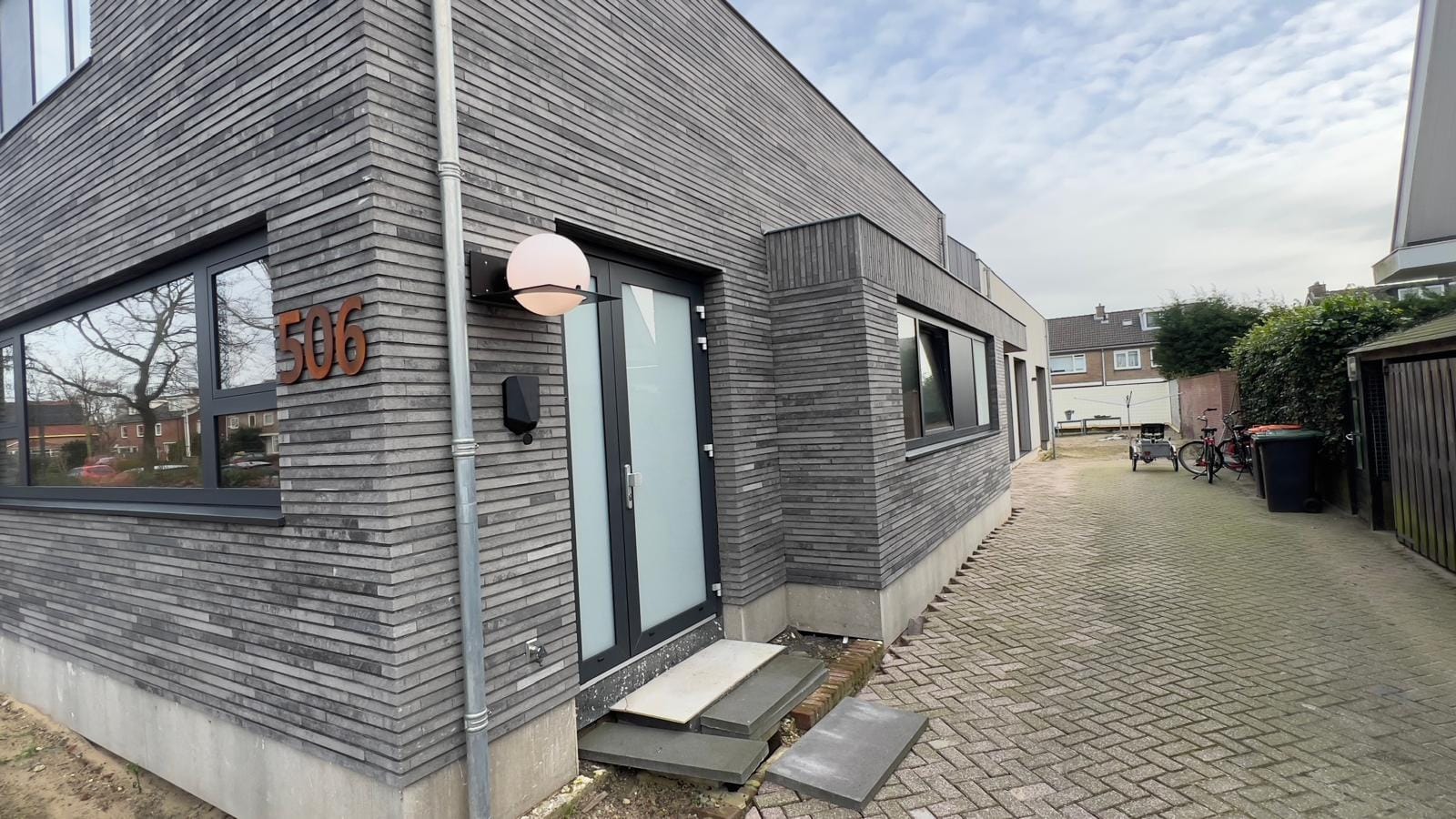 Moderne entreegevel met grijze langformaat steenstrips, nieuwbouwwoning Heiloo