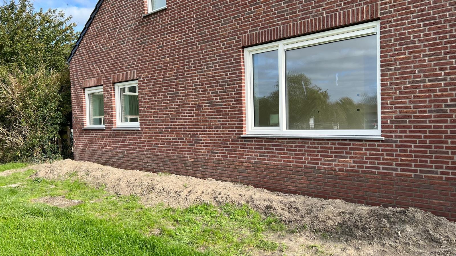 Lange gevel met rode steenstrips en witte kozijnen, woonhuis Langedijk