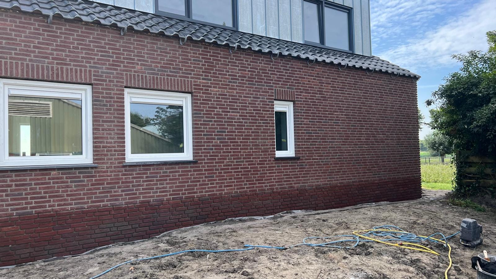 Gevel met rode steenstrips tijdens de afronding, woonhuis Langedijk