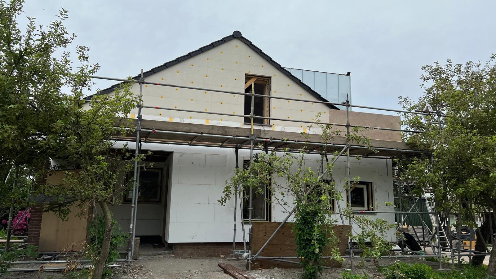 Woning in de steigers tijdens het aanbrengen van gevelisolatie en steenstrips, Langedijk