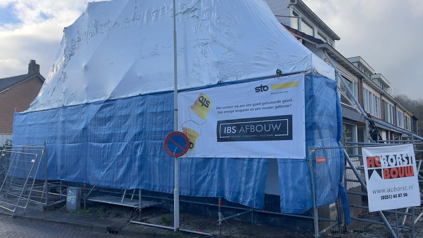 Ingepakte steiger met IBS Afbouw-doek tijdens de gevelrenovatie, Limmen