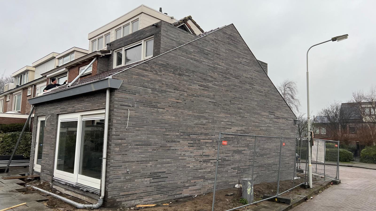 Gevel met grijze minerale steenstrips na na-isolatie, woonhuis Limmen