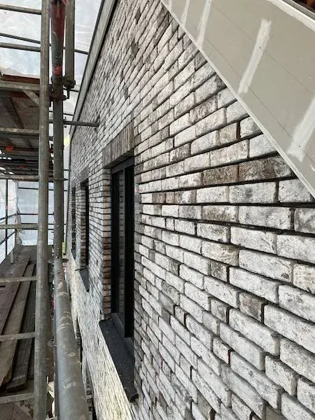 Gevel met genuanceerde steenstrips op beton tijdens de montage