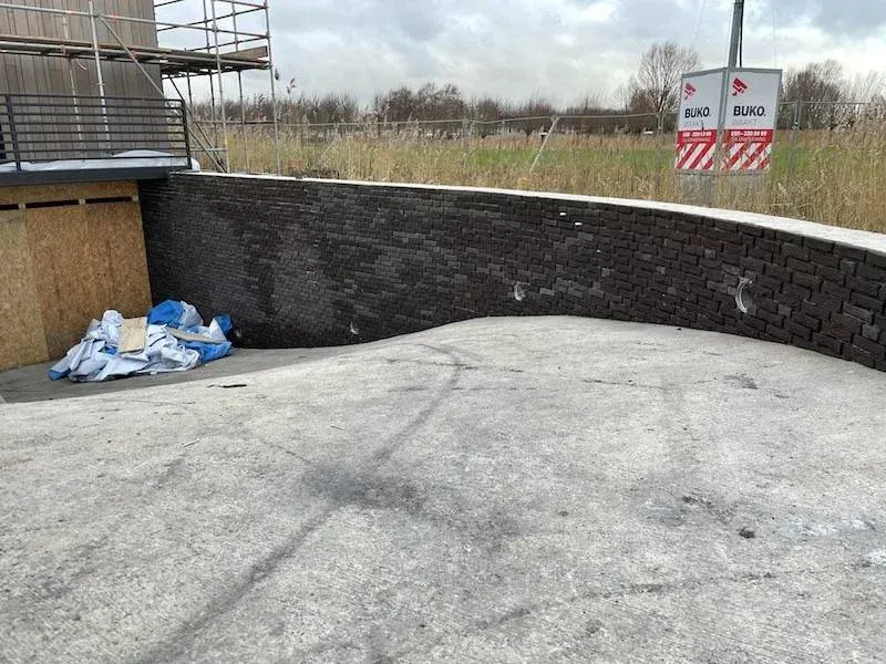 Gebogen betonwand bekleed met donkere steenstrips