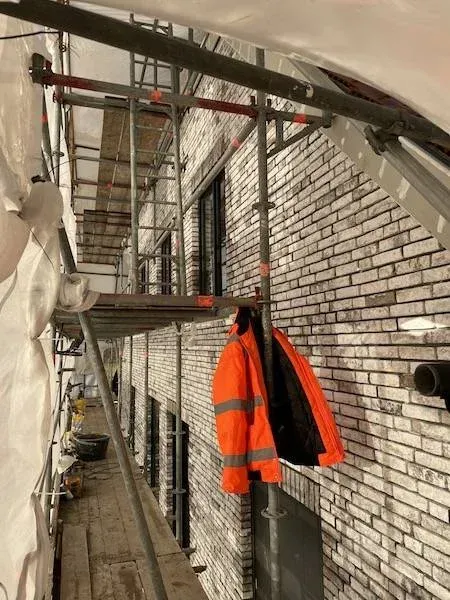 Steigerwerk langs de gevel met steenstrips op beton